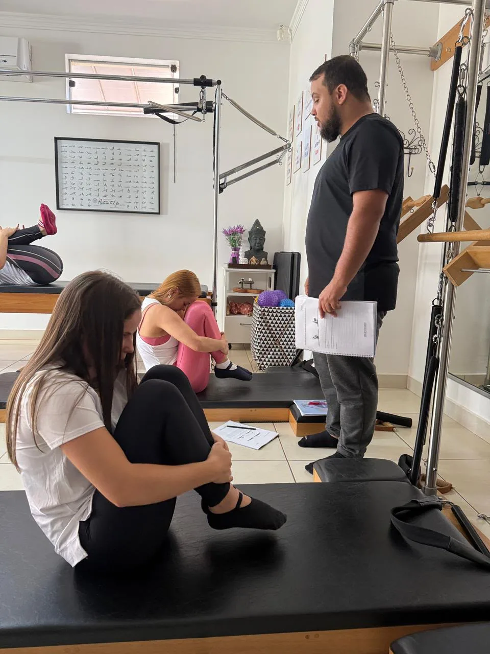 Alunas praticando exercícios no solo enquanto são acompanhadas pela equipe
